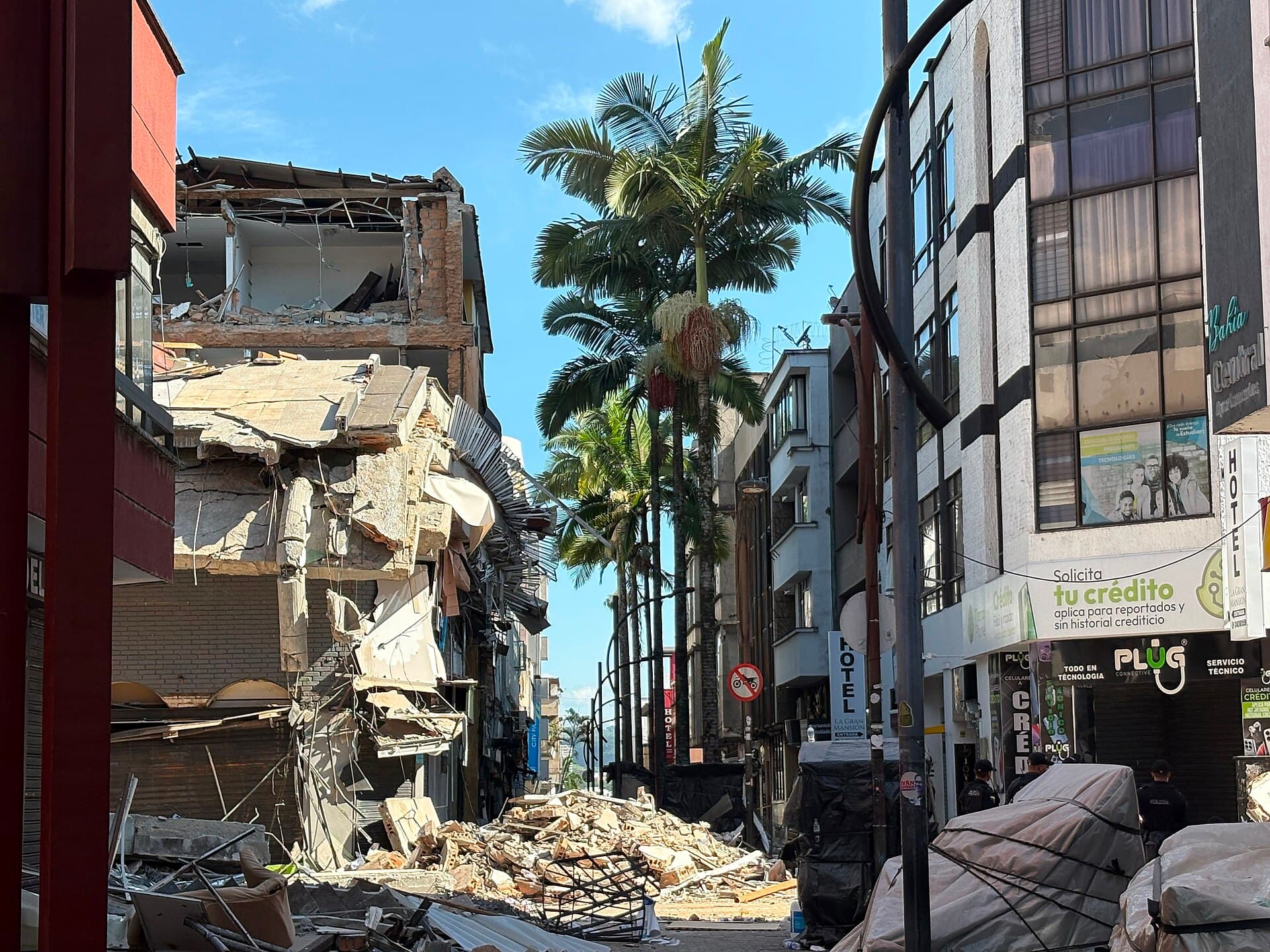 A street in Colombia with a partly collapsed building beside palm trees